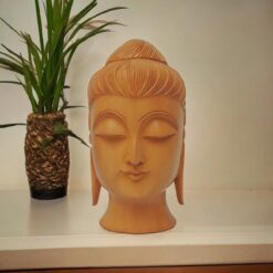 Wooden Buddha head statue placed on a wood table top