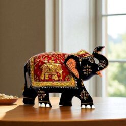 Indian decorative black elephant figurine with vibrant patterns and golden motifs on wooden table.