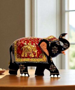 Indian decorative black elephant figurine with vibrant patterns and golden motifs on wooden table.