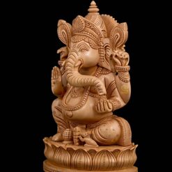 Wooden Ganesha statue with carved lotus pedestal and black background.