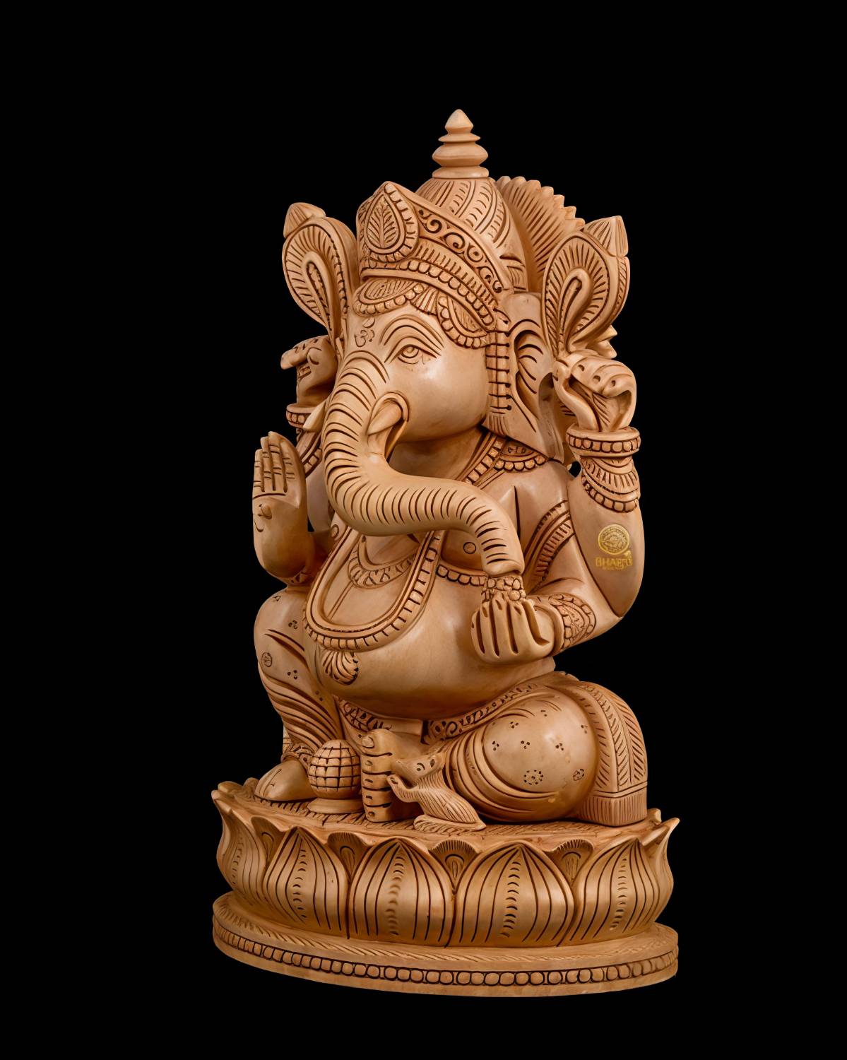 Wooden Ganesha statue with carved lotus pedestal and black background.