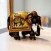 Carved wooden elephant figurine with hand-painted Indian ceremonial details on a tabletop.