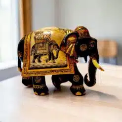 Carved wooden elephant figurine with hand-painted Indian ceremonial details on a tabletop.