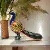 Colorful ceramic peacock sculpture with intricate floral patterns and a vibrant tail.
