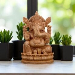 Beautiful wooden Lord Ganesha statue with symbolic arms, facing a natural, serene setting.