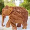 Intricately carved wooden elephant sculpture with detailed patterns, tusks, and natural wood finish.