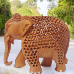 Intricately carved wooden elephant sculpture with detailed patterns, tusks, and natural wood finish.