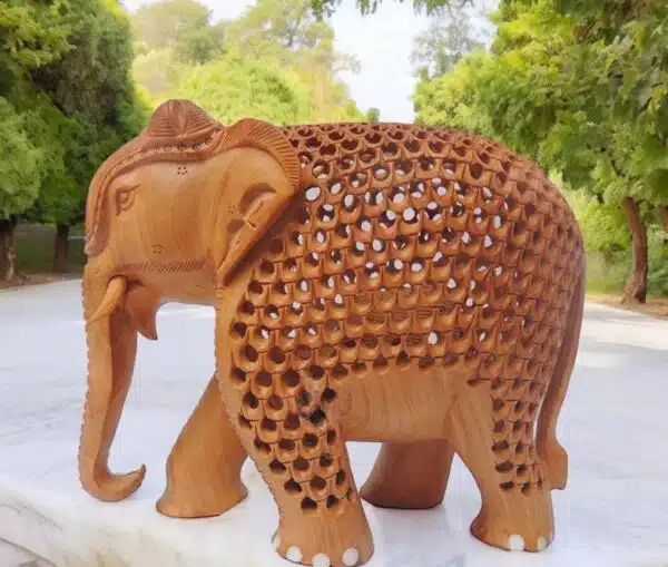 Intricately carved wooden elephant sculpture with detailed patterns, tusks, and natural wood finish.