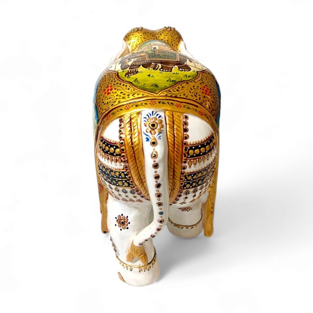 Decorative ceramic elephant sculpture with detailed village scene, gold accents.