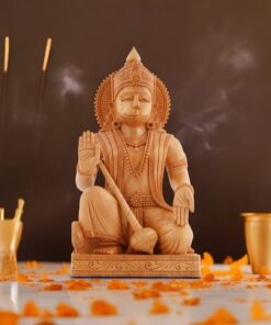 Wooden Hanuman ji statue with intricate carvings, flower petals, incense, and ceremonial offerings in a spiritual setting.
