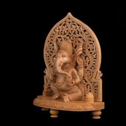 Wooden Ganesha statue with intricate carved arch and ornate devotional details.