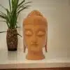 Wooden Buddha head statue placed on a wood table top