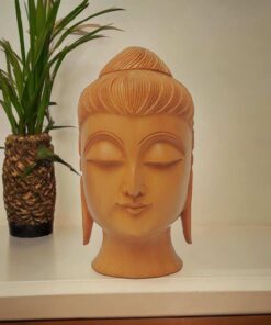 Wooden Buddha head statue placed on a wood table top