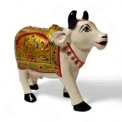 Decorative white cow figurine with golden floral details, traditional Indian craftsmanship, cultural symbol.