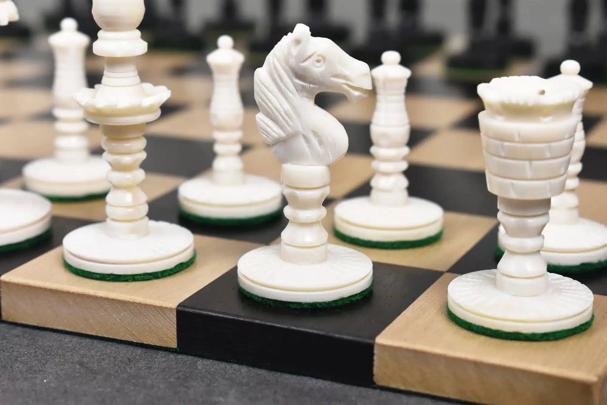 Elegant camel bone chess set with detailed white and black chess pieces on a crafted checkered board.