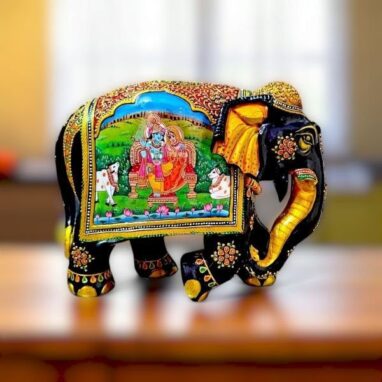 Wooden hand- painted elephant statue on a table in room and RadhaKrishna statue hand painted on it