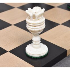 Ornate ivory chess rook with flower-shaped top on classic wooden chessboard.