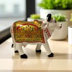 Handcrafted painted cow figurine with gold, red, and green floral motifs for prosperity and decor.