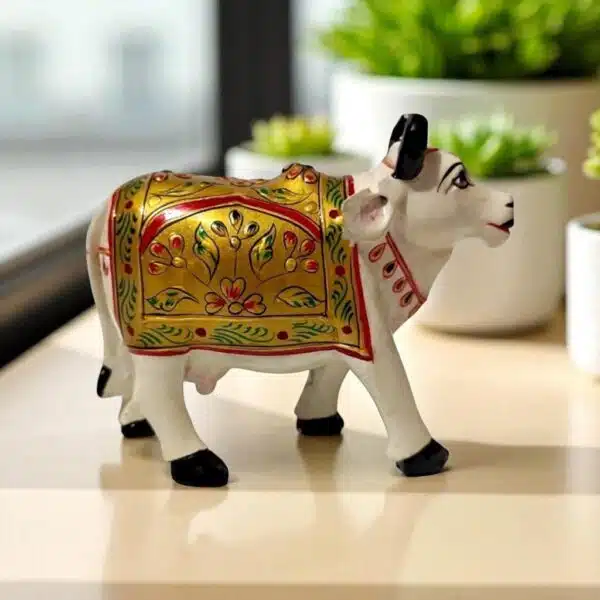Handcrafted painted cow figurine with gold, red, and green floral motifs for prosperity and decor.