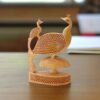 Intricate wooden peacock sculpture with a baby peacock and honeycomb-patterned feathers.