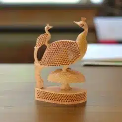 Intricate wooden peacock sculpture with a baby peacock and honeycomb-patterned feathers.