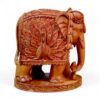 Hand-carved sandalwood elephant figurine with ornate peacock design and decorative base.