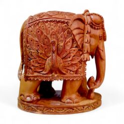 Hand-carved sandalwood elephant figurine with ornate peacock design and decorative base.