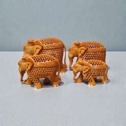 Decorative wooden elephant figurines with carved floral patterns on gray tabletop.