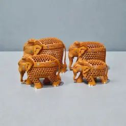 Decorative wooden elephant figurines with carved floral patterns on gray tabletop.