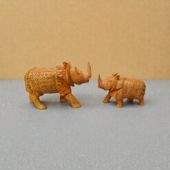 Decorative carved rhinoceros figurines facing each other on a gray-blue tabletop.
