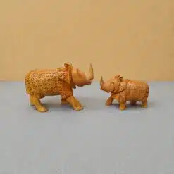 Decorative carved rhinoceros figurines facing each other on a gray-blue tabletop.