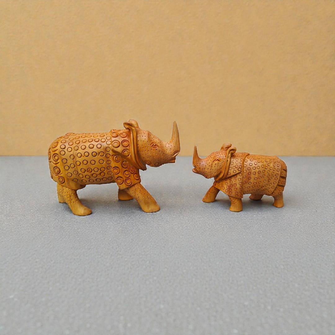 Decorative carved rhinoceros figurines facing each other on a gray-blue tabletop.