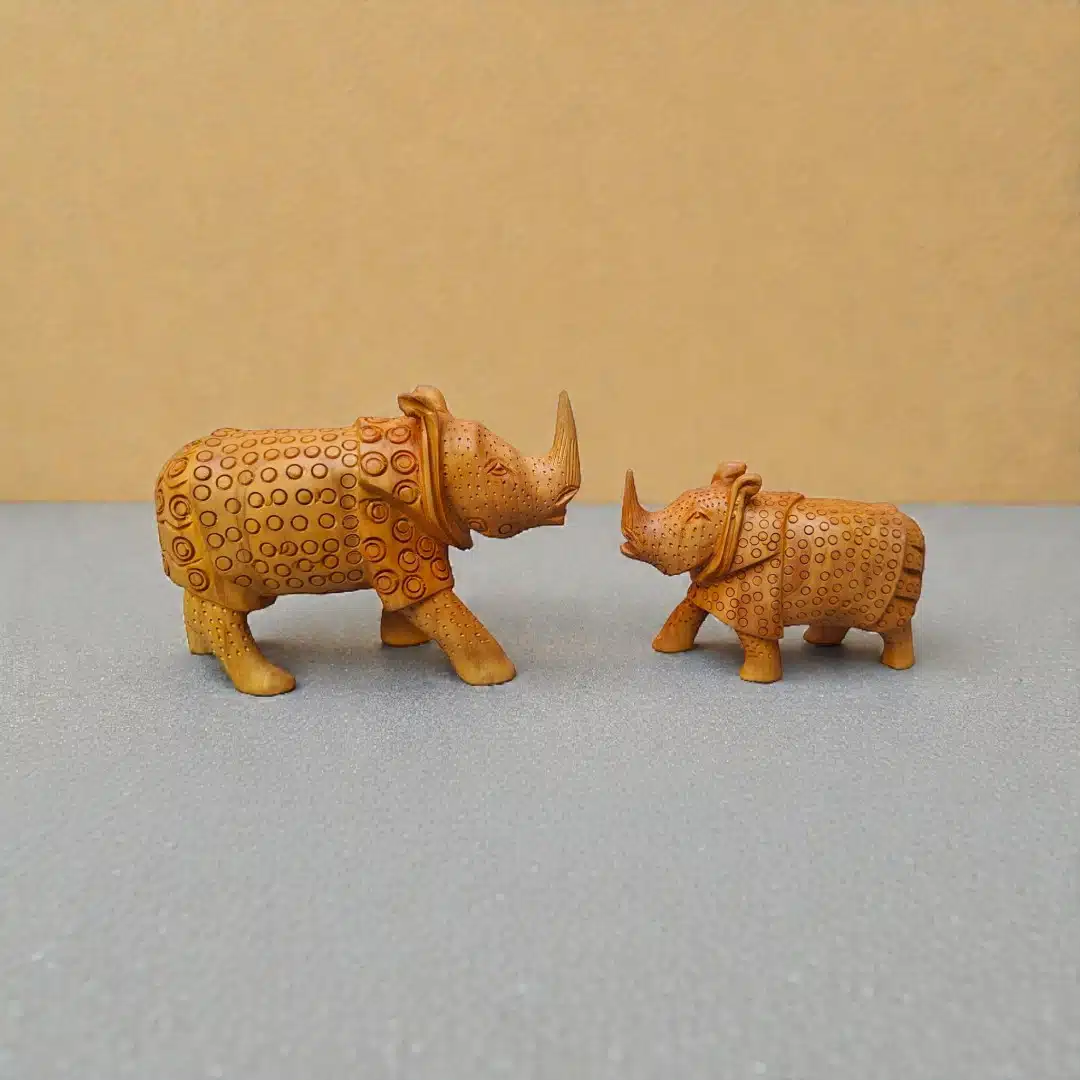 Decorative carved rhinoceros figurines facing each other on a gray-blue tabletop.