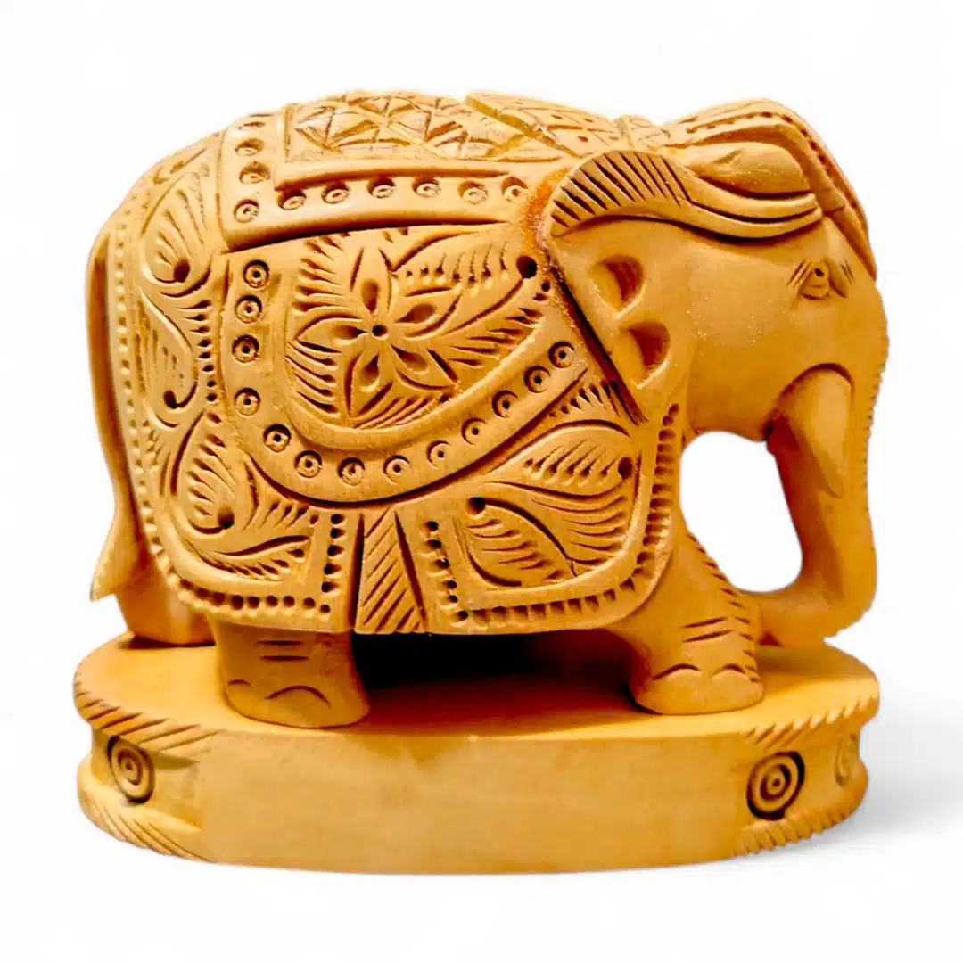 Hand-carved golden elephant figurine with ornate floral patterns on oval pedestal.