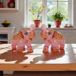 Rose Quartz elephant figurines on sunlit wooden table with plants by window.