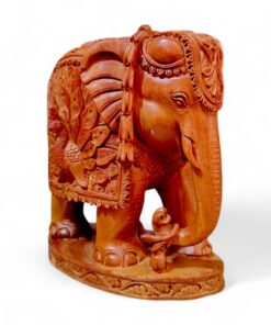 Hand-carved wooden elephant figurine with ornate ceremonial saddle and peacock design.